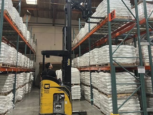 a man in a forklift by a large shelf full of white bags